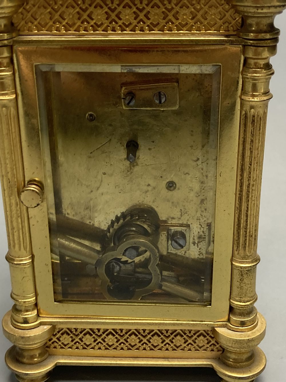 A brass timepiece with four glass panels and filigree decoration